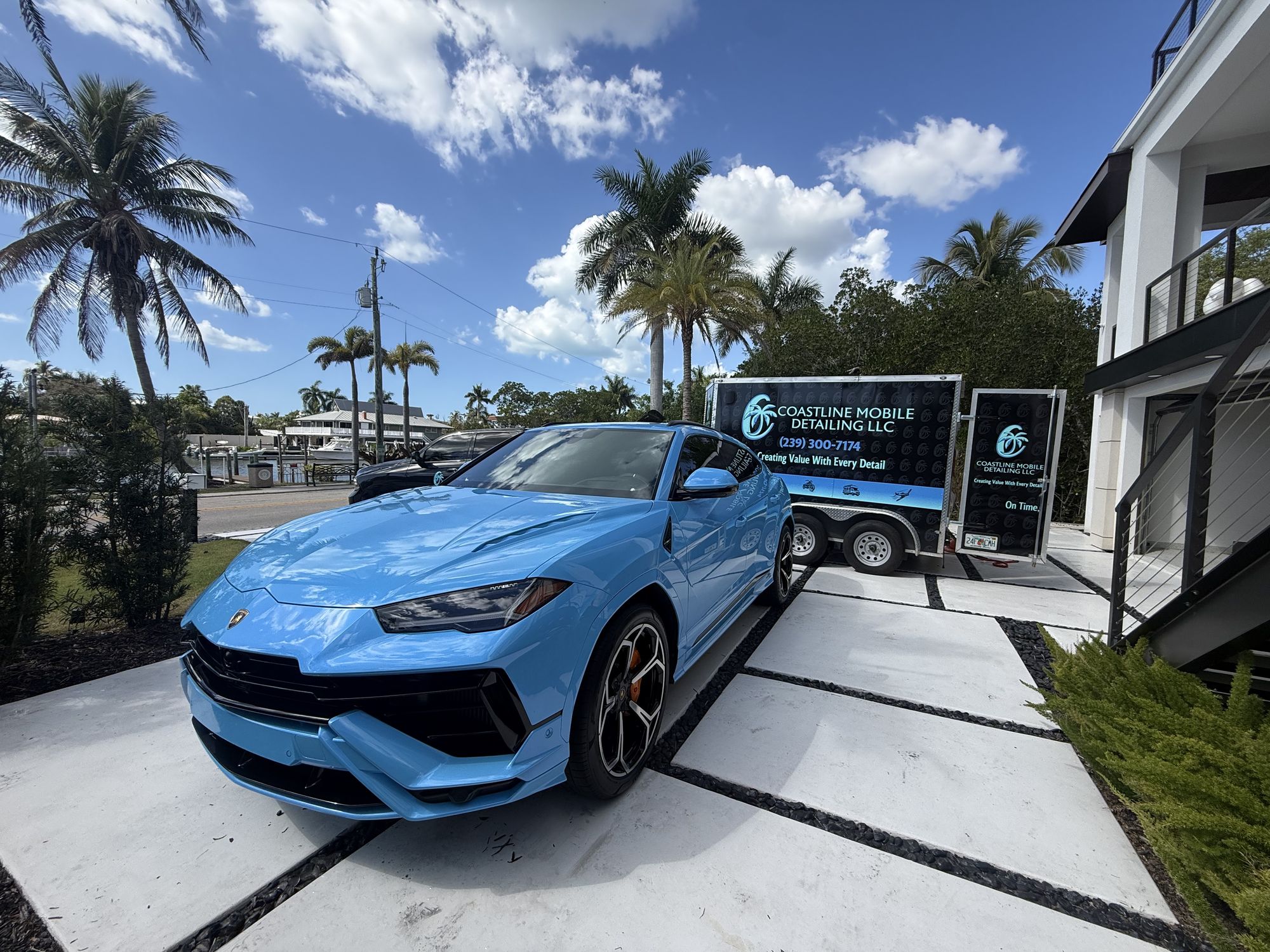 Light blue Lamborghini Urus parked canal-side in Naples with the Coastline branded trailer