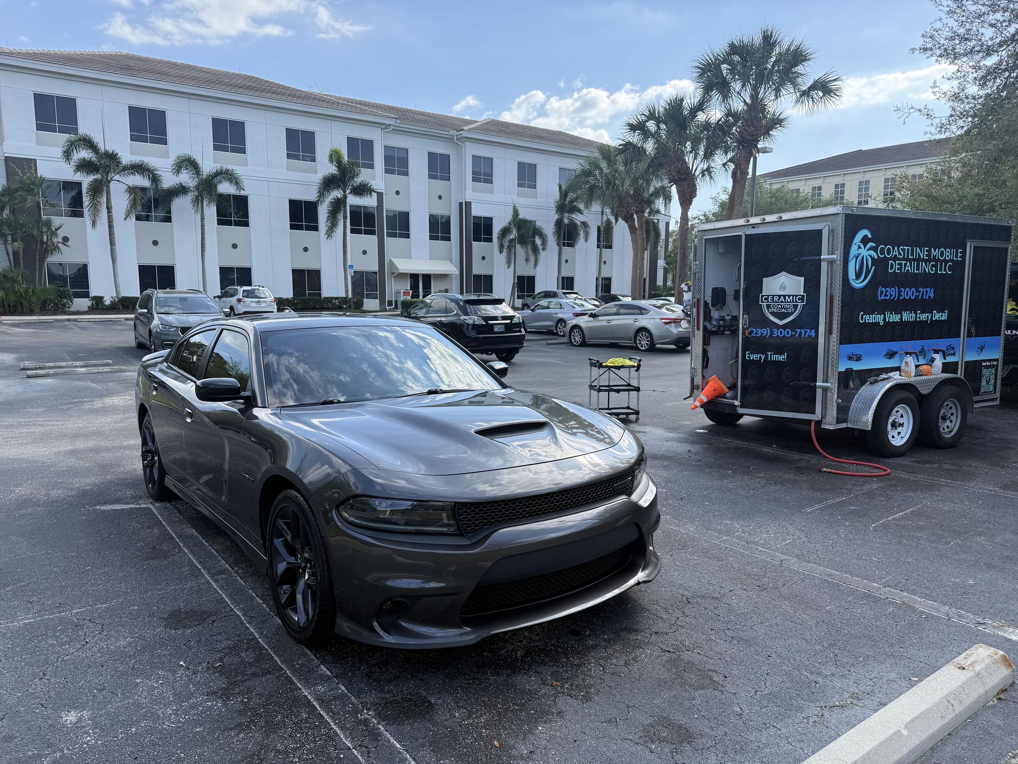 Dodge Charger being detailed in an office parking lot in Naples with the Coastline trailer parked beside it