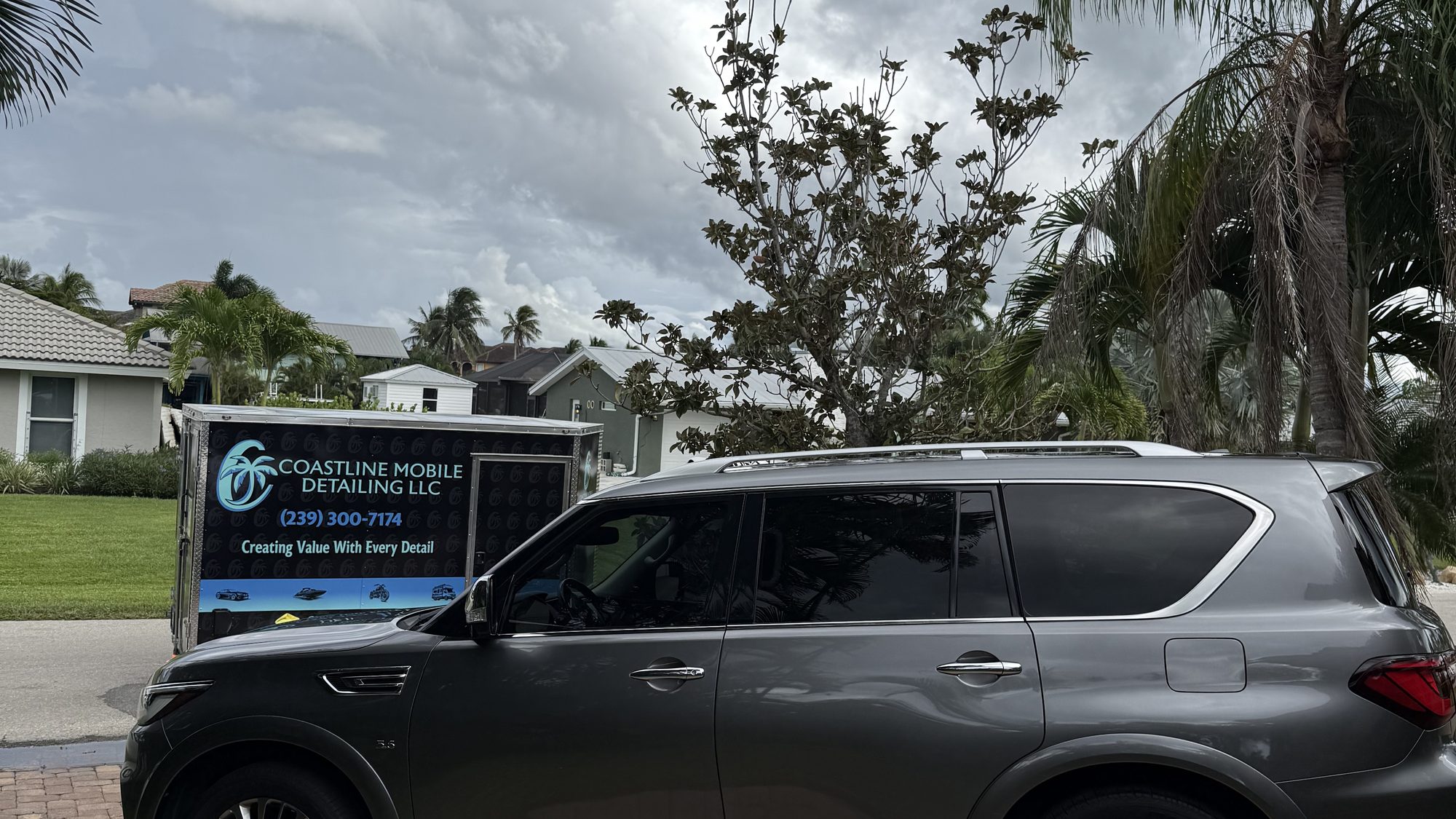 Luxury SUV in a client driveway with the Coastline trailer parked at the curb